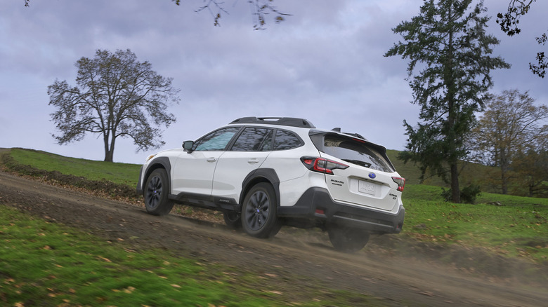 Subaru Outback driving up a dirt country road