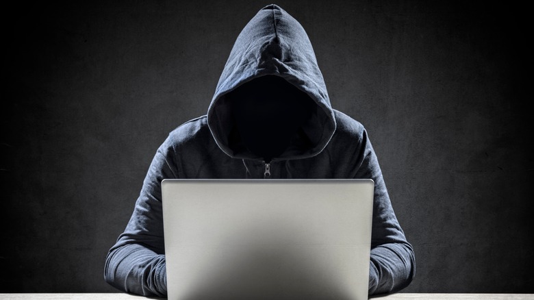cybercriminal in hoodie with laptop