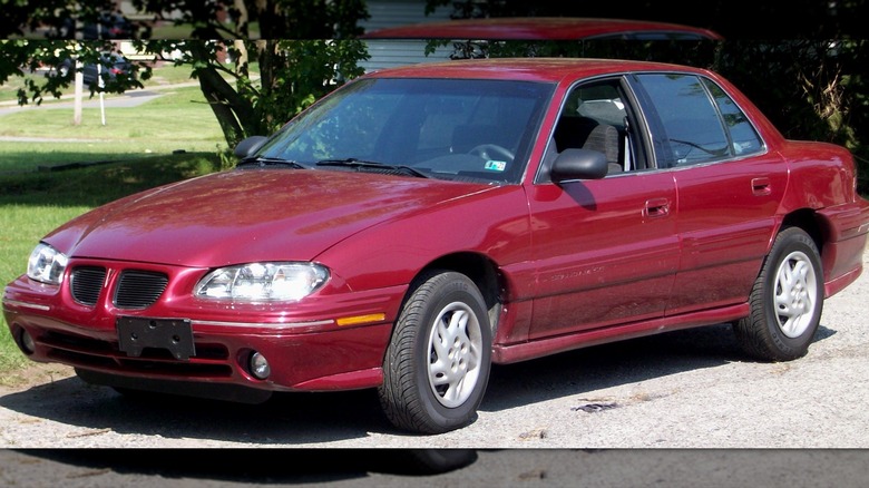 Red 1996 - 1998 Pontiac Grand Am parked on gravel