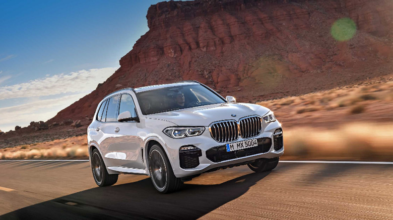 A white BMW X5 driving on a desert highway