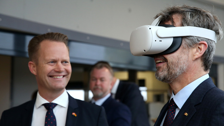 Crown Prince Frederik of Denmark (R) tries out virtual reality goggles next to Danish Foreign Minister Jeppe Kofod