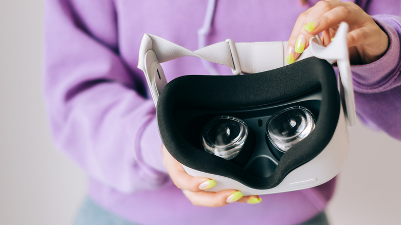 A woman holds a Meta Quest 2 VR headset