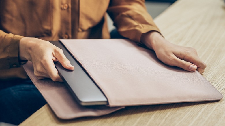 woman in a yellow shirt taking her laptop pc out of the bag at work.