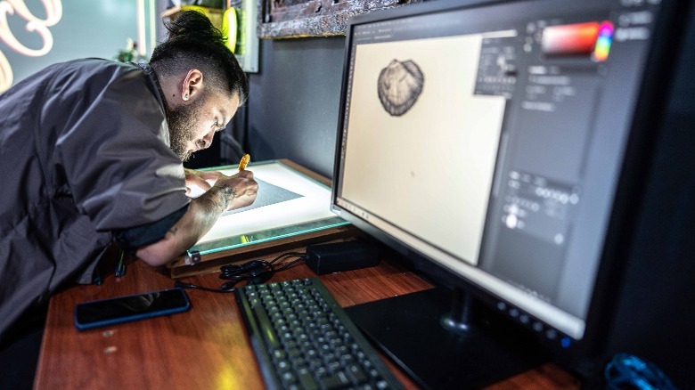 man designing on paper, Photoshop on computer