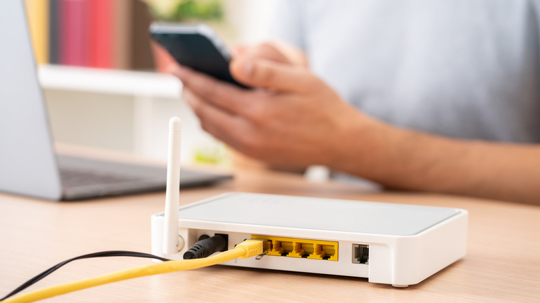 hands holding phone near router