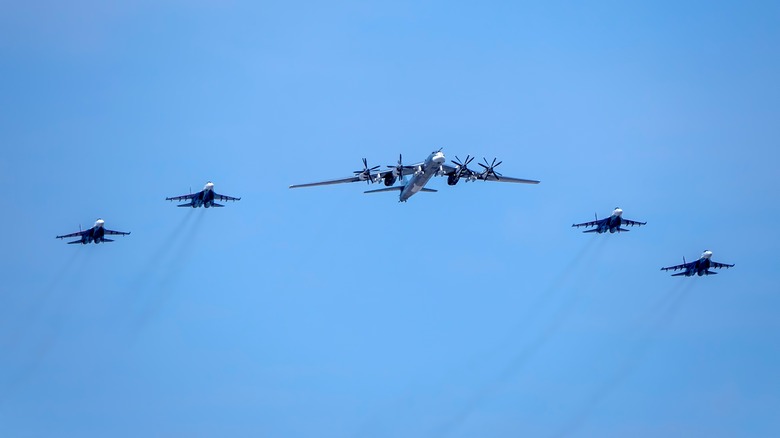 Tu-95 flanked by fighter jets