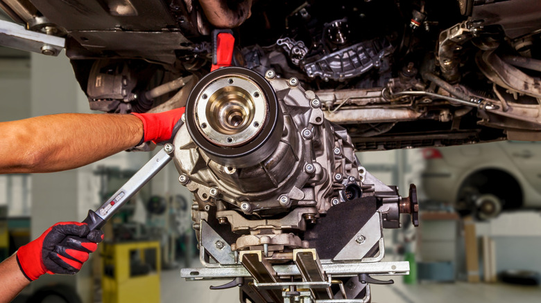 Mechanic working on raised vehicle component