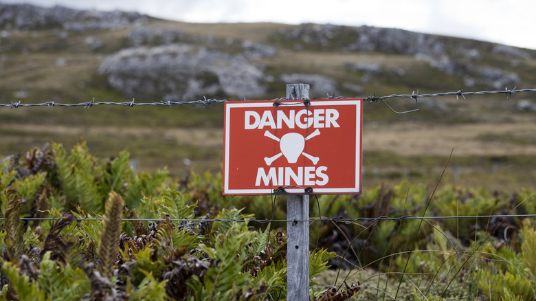 Warning sign posted in a field that landmines are present