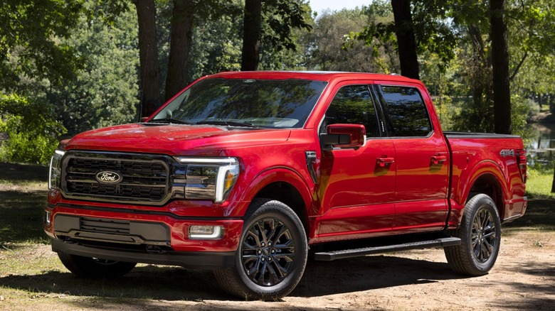 Red Ford F-150 Lariat parked on dirt