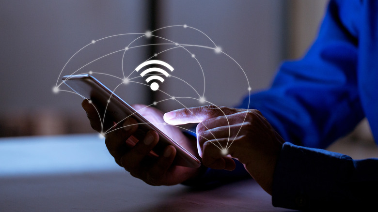A person holds a smartphone, wi-fi logo is overlaid