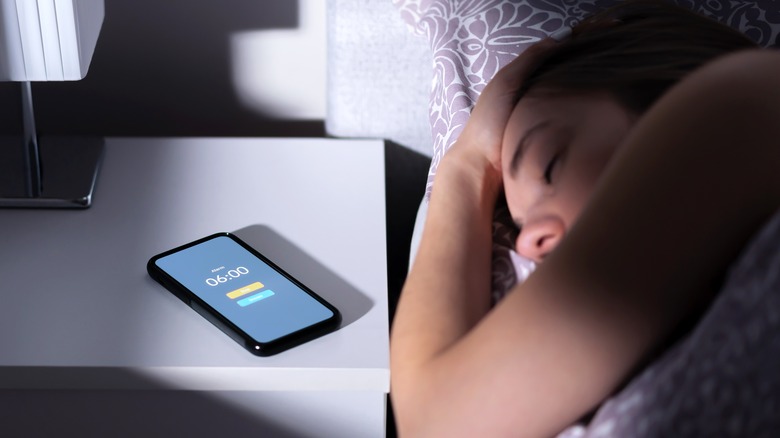 Woman sleeps while phone alarm rings