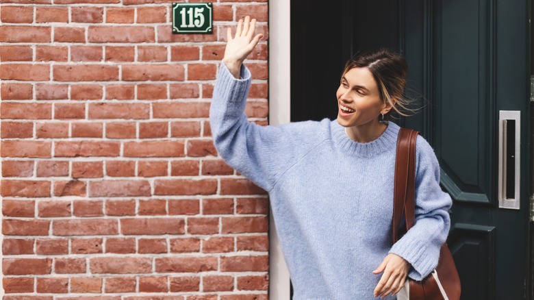 Woman leaving apartment and waving