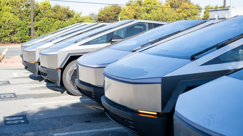 Tesla Cybertrucks lined up near a Tesla dealership