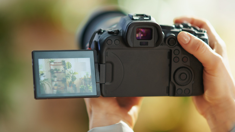 Person holding a modern Mirrorless Camera with tilting back screen