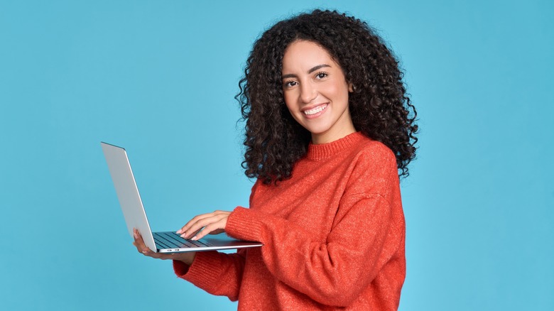 smiling student with laptop on blue background