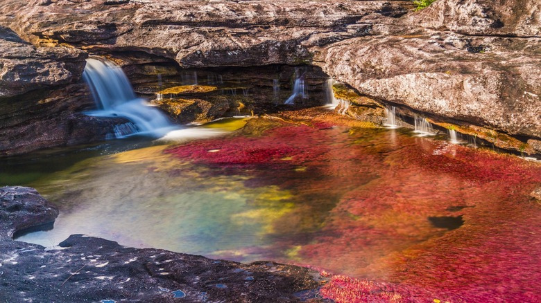 waterfall into a pink lake next to a rock formation