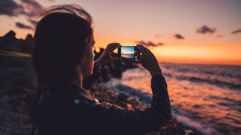 person taking a photo of the sunset on a smartphone