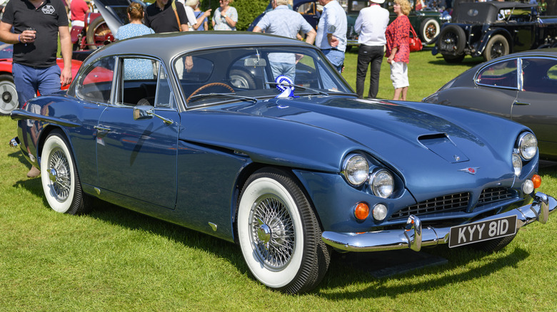 A blue Jensen CV8 on display in a field.