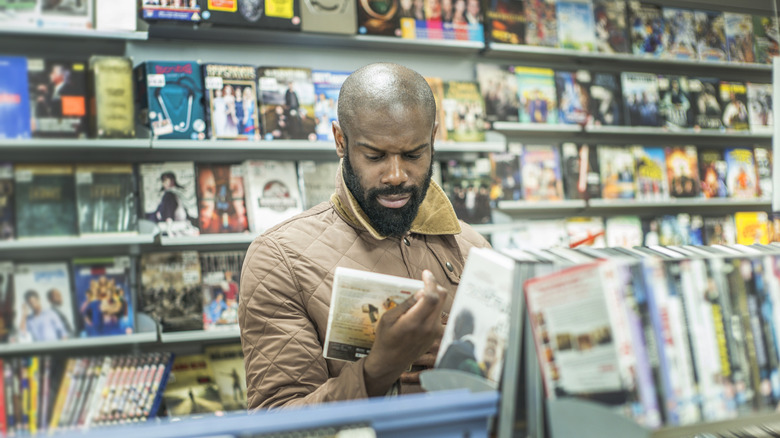 man looking at DVD in shop