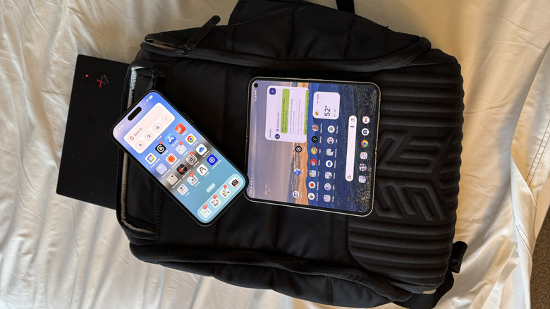 Backpack with laptop and two smartphones on top of a bed