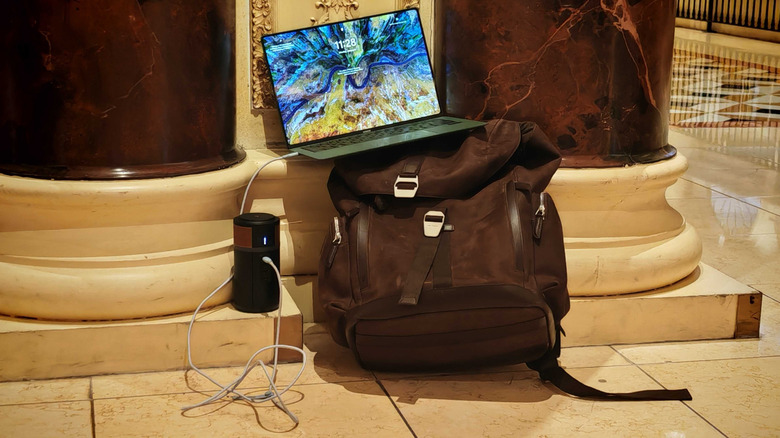 Windows 11 laptop charging via Duracell power bank on top of a backpack at CES show floor