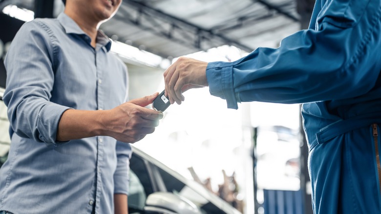 man passing key at auto shop