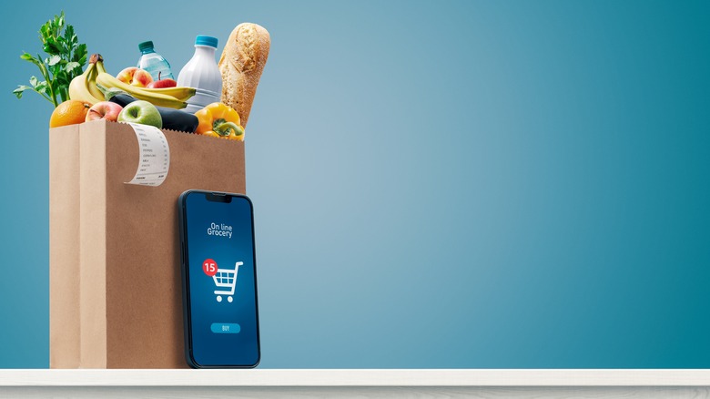 Smartphone next a grocery bag full of items 