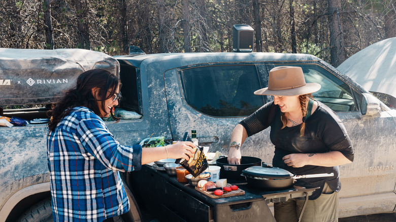 Two people cook outdoors on the Rivian kitchen 