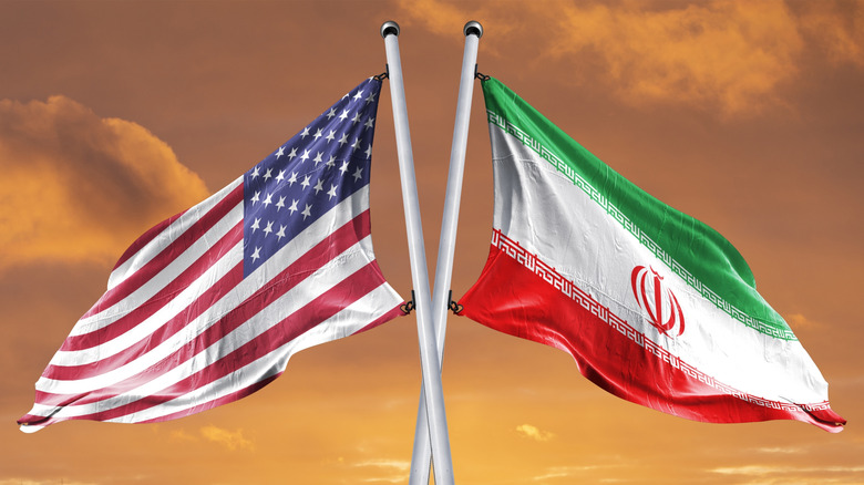 American and Iranian flags flying beside each other, waving in opposite directions