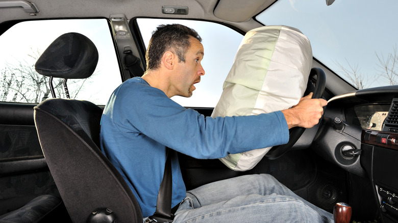 Man facing a deployed airbag in a car crash