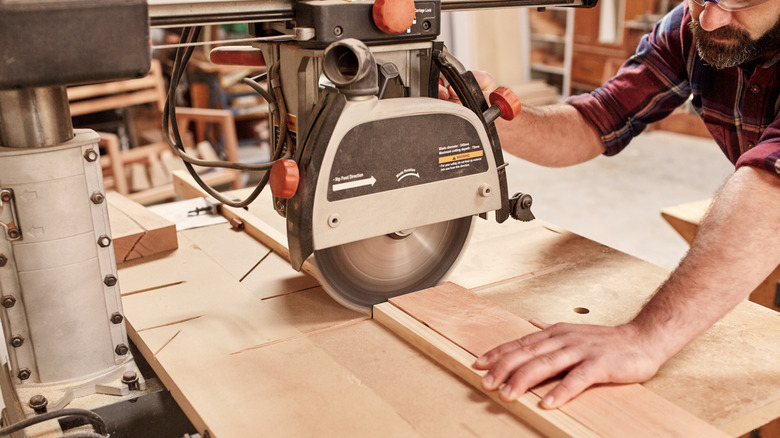 A person using a radial arm saw to cut wood.