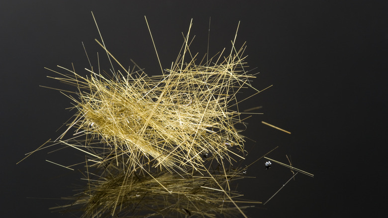 Pele's hair on black reflective surface