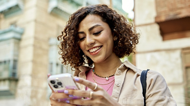 woman with curly hair and rings looking at phone 