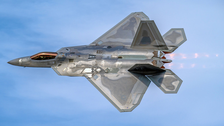 An F-22 Raptor flying with afterburners fully lit in July 2023