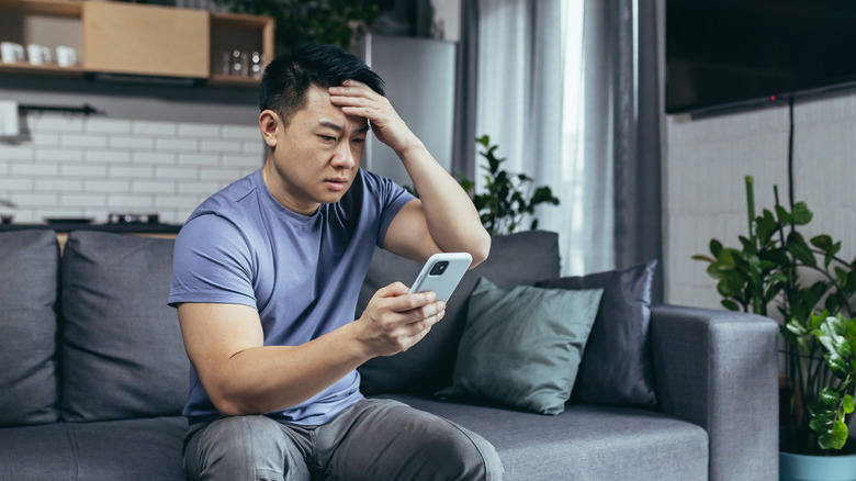 Confused man looking at iPhone