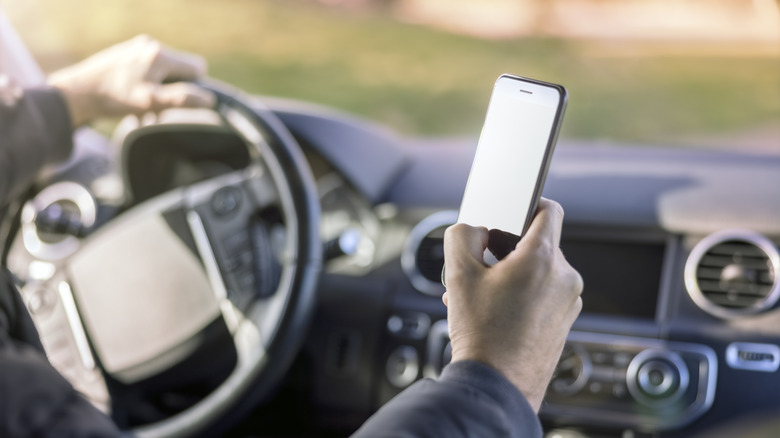 A person texting on an iPhone while driving