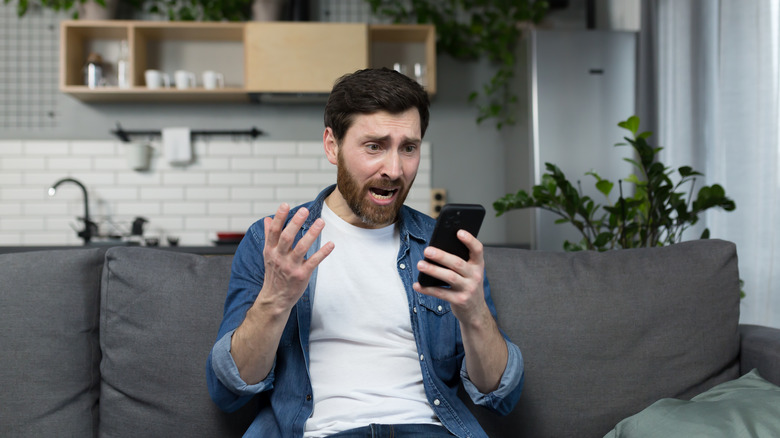 an iPhone user looks at his phone in abject horror