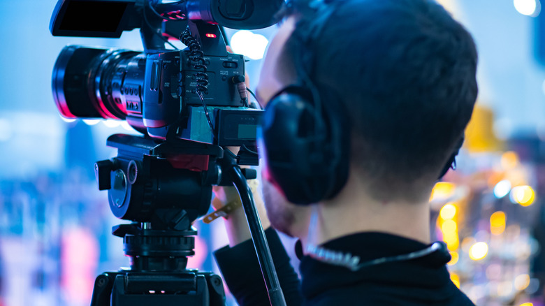 man using video camera mounted to tripod