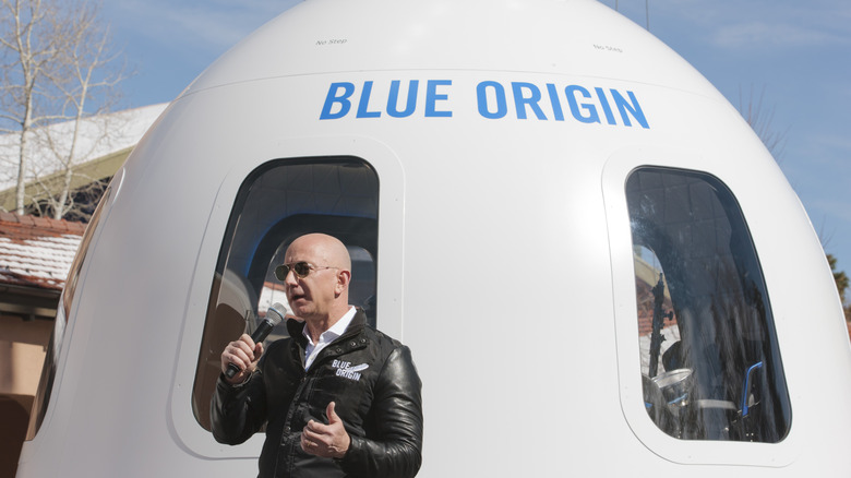 Jeff Bezos speaking in front of a Blue Origin spacecraft