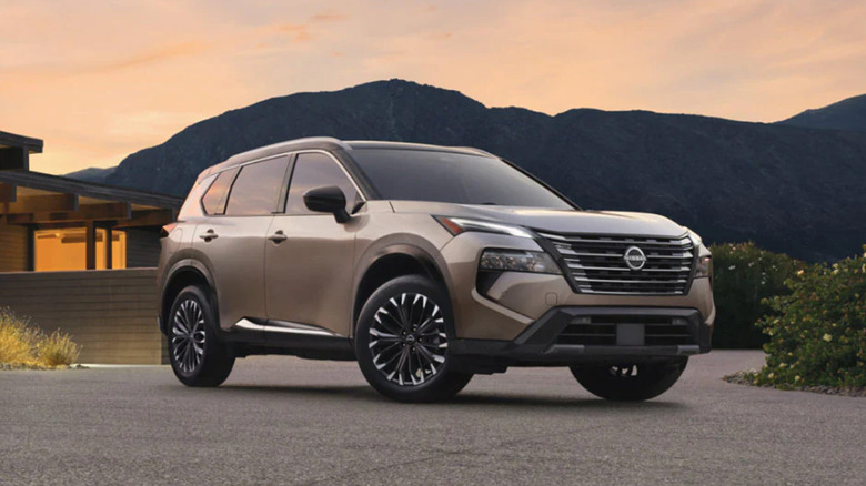 A tan Nissan Rogue in a driveway at sunset