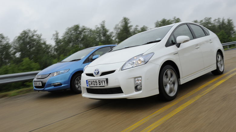 white Toyota Prius passing Honda