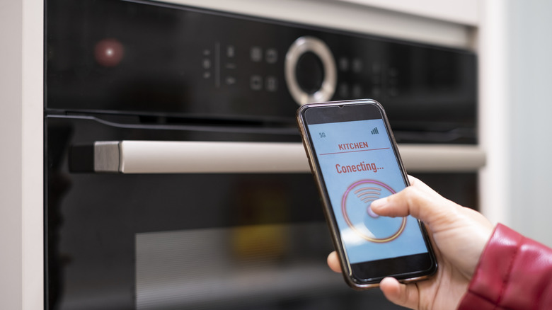 A person connecting their smart phone to a smart kitchen