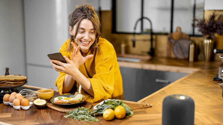 A person talking to an Alexa speaker in their kitchen