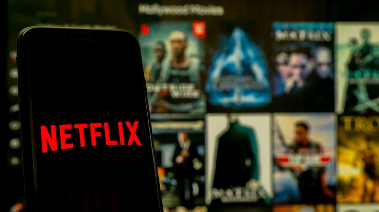 Netflix logo on a smatphone with Netflix's library blurred in the background