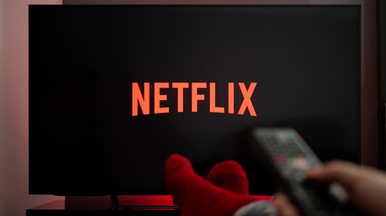 Viewer pointing remote at TV with Netflix dispalyed