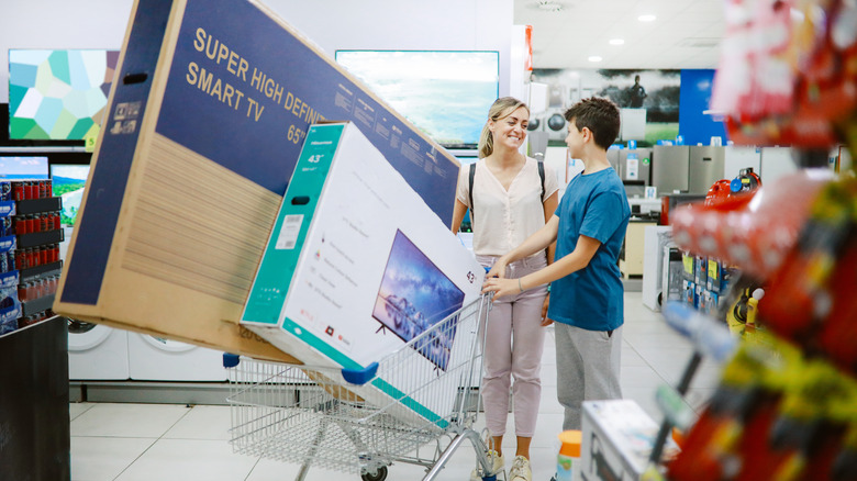 Mother and son with multiple TVs in a shopping cart