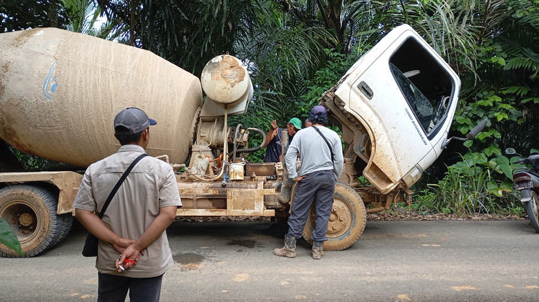 Workers inspect broken-down cement truck