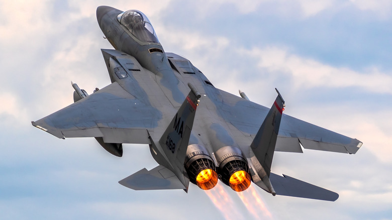 An F-15 Eagle flying upward with its afterburners engaged.