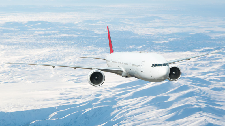 An airplane flying over snowy mountain ranges.