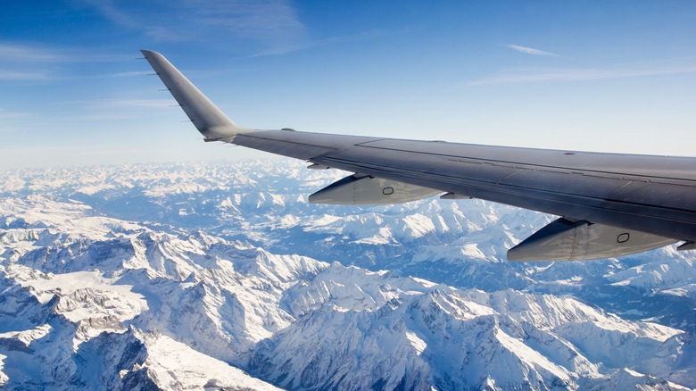 An airplane flying over snow-covered mountains.